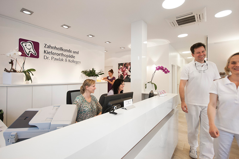 Freundlicher Empfangsbereich der Praxis Dr. Pawlak & Kollegen mit Mitarbeiterinnen und Zahnärzten